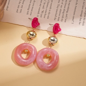 Detailed close-up of pink resin marble earrings with gold metal beads and vintage background
