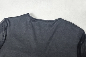 Detail of round neckline with mesh sleeve stitching on minimalist black dress