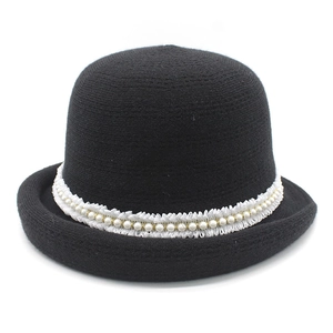 Detail of knitted winter cloche hat featuring elegant white lace and pearl embellishments