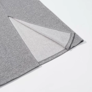 Detailed macro view of the side slit design and stitching on a grey knit polo set