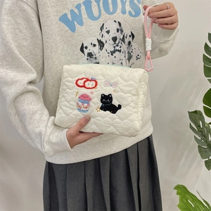 Detail van witte gewatteerde cosmetische tas met schattig borduurwerk en roze koord.