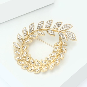 Elegant gold olive branch wreath brooch with sparkling rhinestones on a clean white display