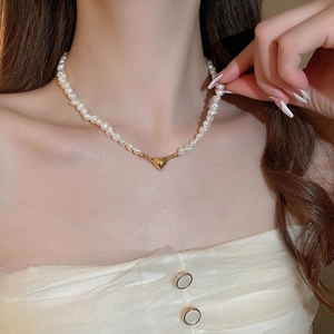 Close-up of heart charm necklace with freshwater pearls on model's neckline