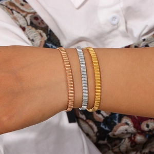 Close-up of minimalist vertical ribbed texture bracelets in rose gold, silver, and gold