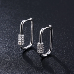 Detail view of silver U-shaped huggie earrings with cubic zirconia stones on black background