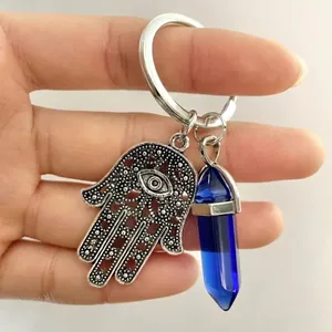 Detail view of silver Hamsa Hand keychain with evil eye and blue hexagonal crystal
