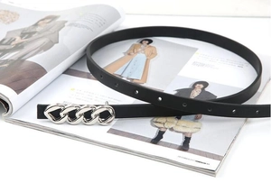 Detail of slim black PU leather belt with silver chain buckle on a fashion magazine