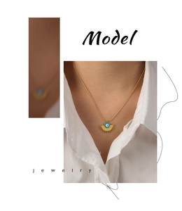 Close-up of golden fan-shaped evil eye pendant necklace with radiant solar ray details