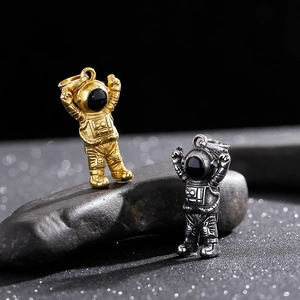 Close-up of gold and silver astronaut pendants on dark stone with metallic finish