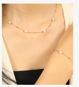 Detail of 18k gold plated necklace and bracelet set featuring baroque pearls on model