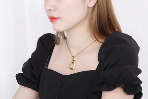 Close-up of heart-shaped hollow pendant necklace worn on neck by a fashion model