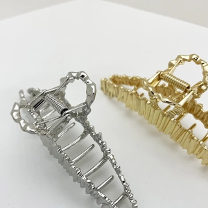 Detail shot of oversized gold and silver hair claws with irregular wavy metal texture