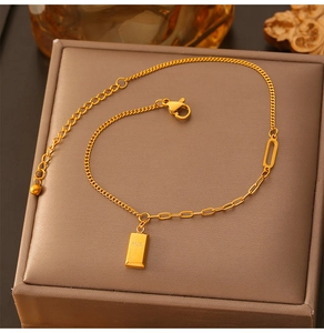 Macro detail of gold-plated titanium steel anklet with engraved gold bar pendant and lobster clasp