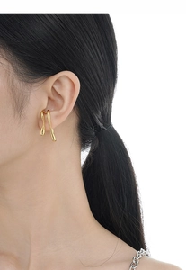 Close-up of minimalist golden irregular earring with fluid organic lines on model