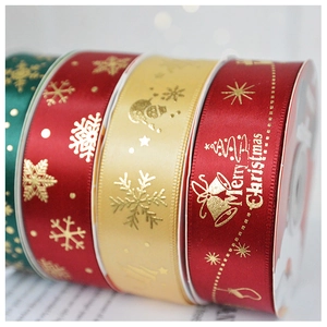 Macro detail of 2.5cm satin ribbons with gold Christmas tree and snowflake patterns