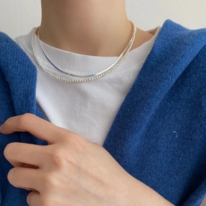 Detail view of 925 sterling silver layered flat snake chain and white pearl choker necklace