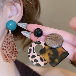 Close-up of leopard print and acetate geometric earrings worn on a person's ear