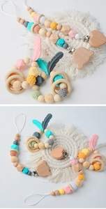 Detail of wooden baby pacifier clips and crochet rattles with silicone feather charms