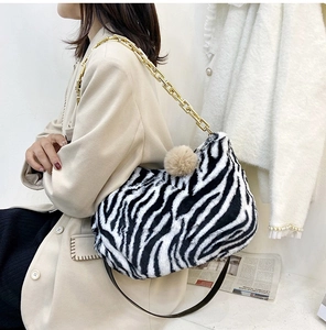 Detail of zebra pattern plush shoulder bag with golden chain strap and fur ball charm