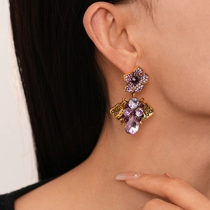 Vintage gold earrings with purple crystal petals and diamonds shown on model
