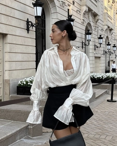 Detail of white long-sleeve blouse with lantern sleeves and silky translucent fabric texture