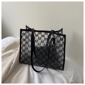 Close-up of clear PVC tote bag with black M-letter print and durable black handles