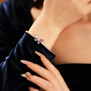 Détail d'un bracelet papillon doré avec zircon violet sur le poignet d'un modèle