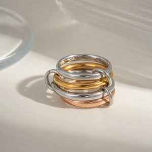 Detailed shot of interlocking tri-color stainless steel rings in gold, silver, and rose gold