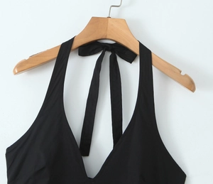 Detail of black halter dress showing deep V-neckline and open back with bow tie detail