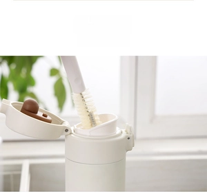 Long handle cleaning brush scrubbing the inside of a narrow white vacuum flask