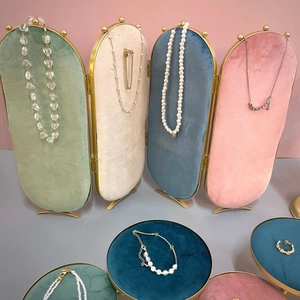 Expositor de joyas de terciopelo con collares de perlas, cadenas de oro y anillos