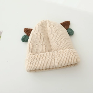 Detail view of ribbed knit texture on cream baby hat with cute brown horns and poms