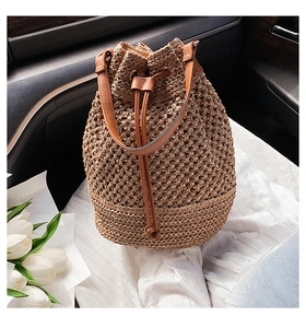 Detail of paper rope woven bucket bag with brown leather handle and drawstring closure