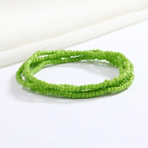 Close-up of emerald green layered glass bead waist chain on white satin background