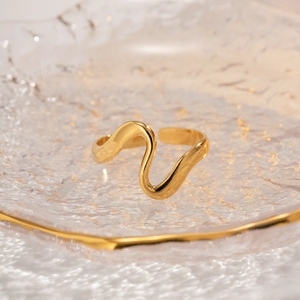Macro shot of polished gold wave-shaped adjustable open ring on textured glass