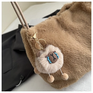 Close-up of soft plush tote bag with gold hardware and a cute animal bag charm