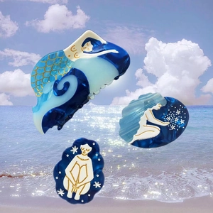 Detail of blue acetate mermaid hair claw clip with gold accents on a beach background