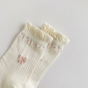 Detail of white ruffle trim cotton socks with breathable mesh and pink bow patterns