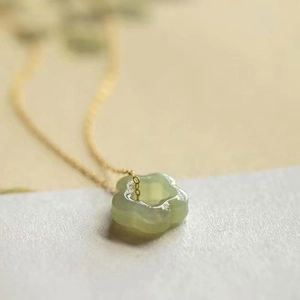 Elegant gold chain necklace with a translucent light green plum blossom jade pendant