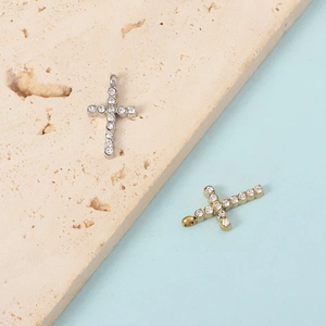 Polished silver and gold cross pendants with sparkling crystals on a stone display