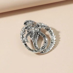Detailed view of a silver dragon brooch with intricate textures and metallic finish