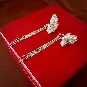 Boucles d'oreilles papillon en zircon à franges argentées sur un écrin à bijoux rouge