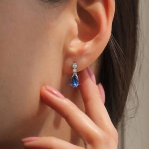 Primer plano de pendientes de lágrima azul oscuro con detalles de diamantes blancos