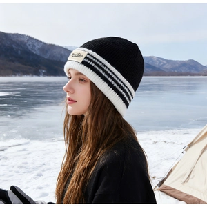 Détail du bonnet en maille rayé PineCrest avec étiquette de marque dans un décor de neige
