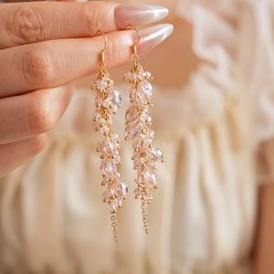 Close-up of bohemian earrings with pink crystal tassels and golden metal hooks