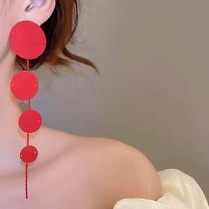 Detail view of long red tassel earrings with four graduated round discs on model