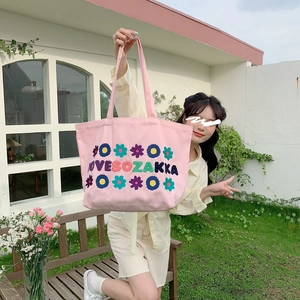 Pink canvas tote bag featuring vibrant floral embroidery and woven shoulder straps