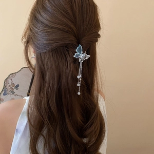 Détail de pince à cheveux papillon argenté avec ailes bleues et franges perlées sur modèle