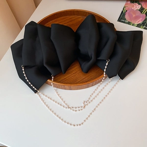 Macro shot of large black satin bow hair clip with triple-layer faux pearl tassel charms