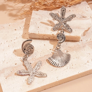 Detailed macro shot of silver nautical earrings with starfish and shell texture detail